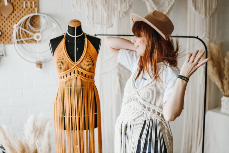 Tailor or seamstress in the atelier fitting the macrame dresse on the dummy. Selective focus